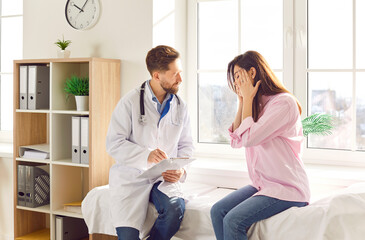 Woman patient suffering from headache or migraine consults with a doctor or nurse during a medical...