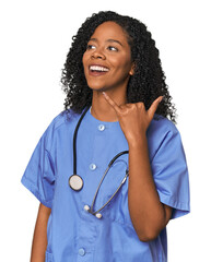 African American nurse in studio background showing a mobile phone call gesture with fingers.