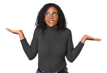 African American woman in studio setting confused and doubtful shrugging shoulders to hold a copy space. - obrazy, fototapety, plakaty