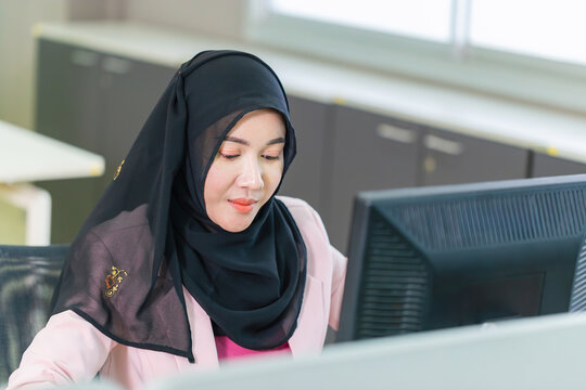 Young Muslim businesswoman in an office, young Arabic woman in a headscarf using a pc computer