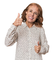 Redhead mid-aged Caucasian woman in studio raising both thumbs up, smiling and confident.