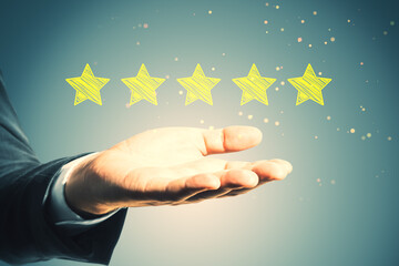 Close up of businessman hand holding 5 star rating on blurry background. Customer service and...