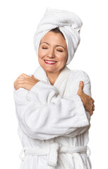 Caucasian woman in bathrobe and towel hugs, smiling carefree and happy.