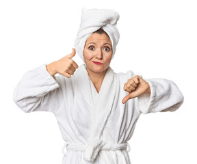 Caucasian woman in bathrobe and towel showing thumbs up and thumbs down, difficult choose concept