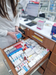 Defocus view inside of pharmacy with female pharmacist stores the medicine inside the drawers and shelves. Healthcare and cosmetics industry blurred background