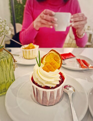 Aesthetics view with a carefree young woman in a cafe enjoys a cup of tea with cupcake