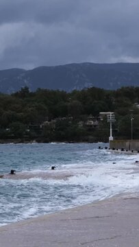 Powerful waves crashing the coast in the harbour of Njivice, Croatia after Storm Ciar&aacute;n smashed into Krk Island. Disquiet sea surface, huge water splashes, boats and yachts rocking in the background.
