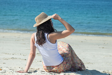 young woman sitting on the beach contemplating the sea