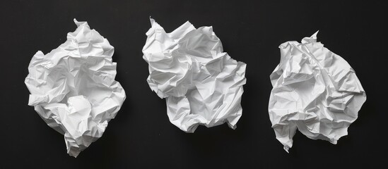 Three crumpled white pieces of paper against a black backdrop.