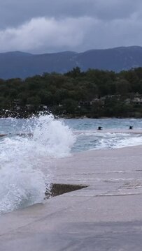 Powerful waves crashing the coast in the harbour of Njivice, Croatia after Storm Ciar&aacute;n smashed into Krk Island. Disquiet sea surface, huge water splashes, boats and yachts rocking in the background.
