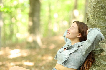 Happy woman relaxing sitting in a forest - 766884892