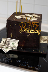 Chocolate cake with dollars and happy birthday inscription.