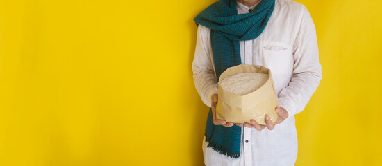 Unrecognizable Moslem man wear scarf and holding sack of rice grain for food donation in Ramadan,...