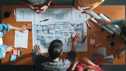 Top view of civil engineer team holding blueprint and standing at table with laptop, project plan...
