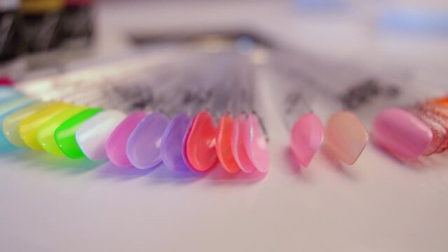 Nail swatch sticks with colorful nail examples on white table.