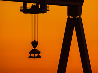 Silhouetted Crane at a Swedish Wharf Against a Vibrant Sunrise Sky