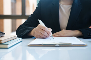 A woman in a suit is writing with a pen on a piece of paper