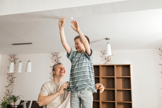 Happy son helping father in peeling old wallpaper from ceiling at home