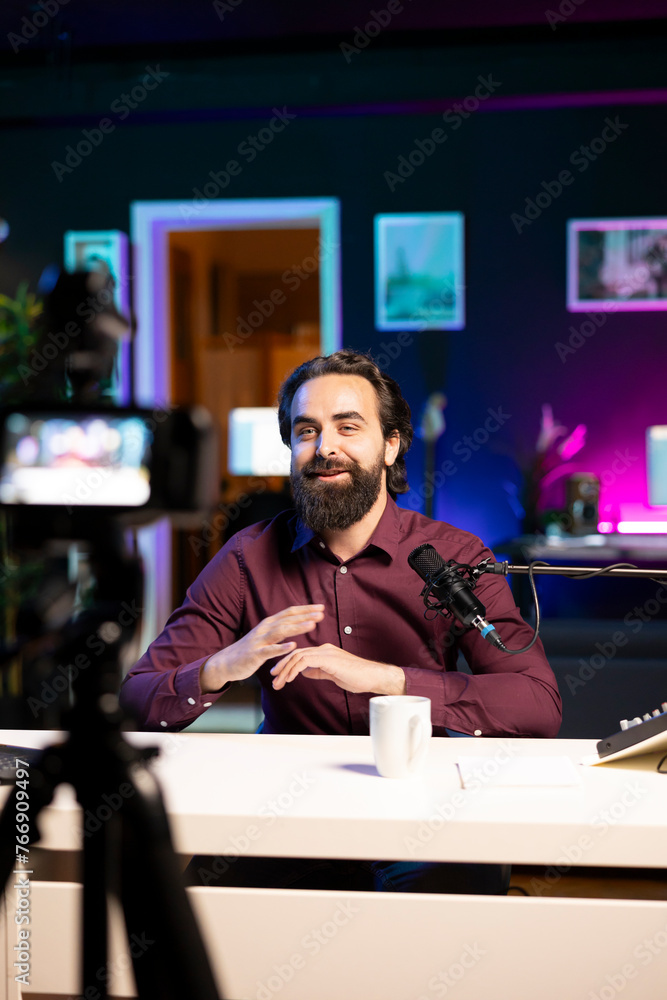 Poster cheerful internet star talking in front on professional camera and quality mic in studio, discussing