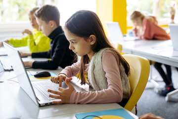 Girl using laptop for programming in classroom