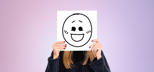 Woman covering face with happy face placard - obrazy, fototapety, plakaty