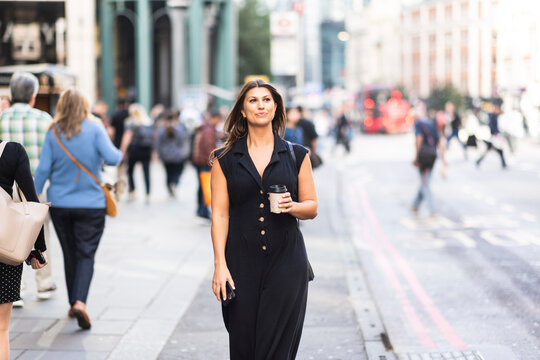 Young woman walking with coffee cup in city of London