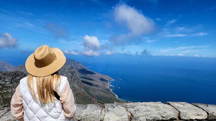 A lady lookdown the sea from Table mountain in South africa