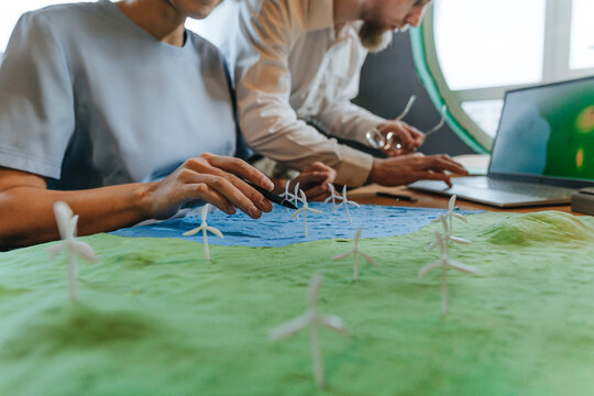 Colleagues with wind power model and laptop in office