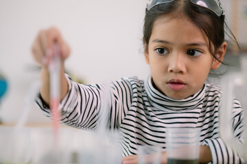 Asian child girl learning science chemistry with test tube making experiment at school laboratory....