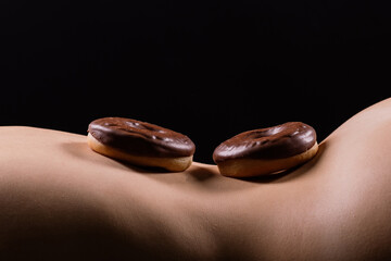 Close up shot of nude woman's body with a chocolate covered donuts