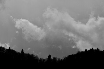 silhouette of a mountain against a cloudy sky in black and white