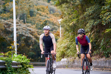 Fototapeta premium young asian adult couple cyclists riding bike on rural road