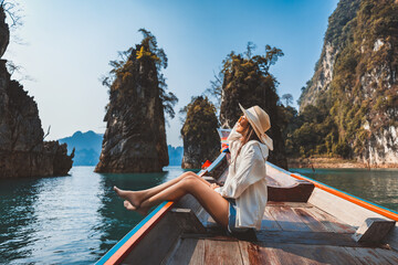 Traveler asian woman relax and travel on Thai longtail boat in Ratchaprapha Dam at Khao Sok National Park Surat Thani Thailand