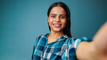 Fototapeta premium Young woman taking selfie portrait, POV shot of a beautiful Asian Indian girl taking her picture