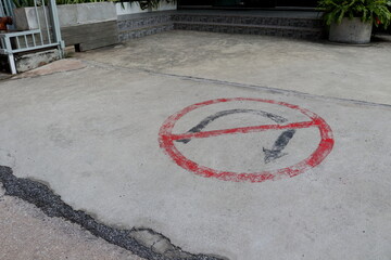 Pale and old No u turn sign on cement floor of entrance of building in Thailand.