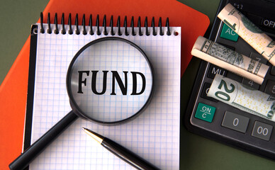 FUND - word under magnifying glass on the background of calculator and banknotes