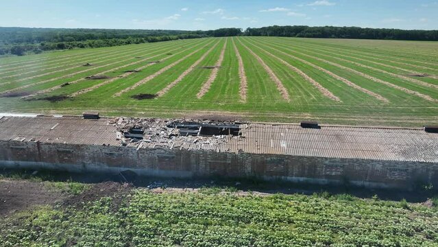 Destroyed grain storage hangar. Craters in the field from rocket fire. Consequences of a rocket attack.