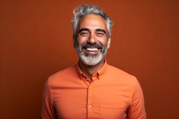 Portrait of a handsome Indian man in orange shirt on brown background