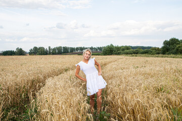 Naklejka na ściany i meble Beautiful blonde girl in a wheat field