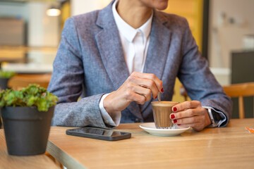 Unrecognizable elegant woman drinking coffee in coffee shop.