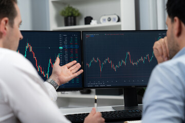Stock traders discussing on research market stock database at real time by using two pc screen for...