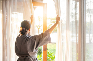 The woman's hand was on the window in the bedroom. She opened the curtains on the window. In the...