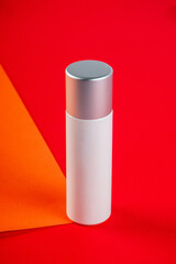 Plastic white tube for cream or lotion. Skin care or sunscreen cosmetic on orange and red background.
