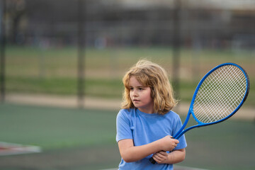 Cute Kid play tennis. Little kid hit tennis ball with tennis racket. Active exercise for kids. Summer activities for children. Child learning to play tennis. Sport Kid hitting Ball on court.