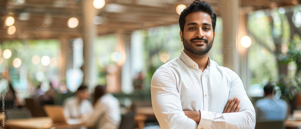 Fototapete Developing strategies to maximize company growth and expansion while standing with a laptop computer in a modern office. An Indian male business analyst assessing technological risks and developing
