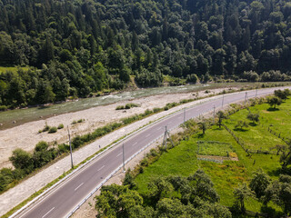 view of a road in the mountains, a river flows between the bridges, a village is located along the road between the mountains, a summer landscape