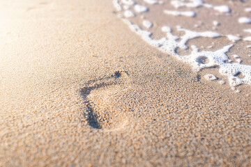 Footprint with golden sand. Beach, wave and footstep on sunny day