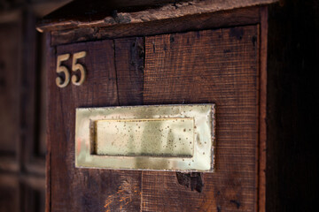 Wooden door and golden letter box  with number 55 with a vintage feel