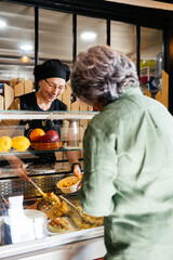 Woman Standing in Front of Counter Filled With Takeaway Food