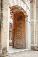 The garden gate of the mosque opening to the outside. A historical wooden door with geometric...